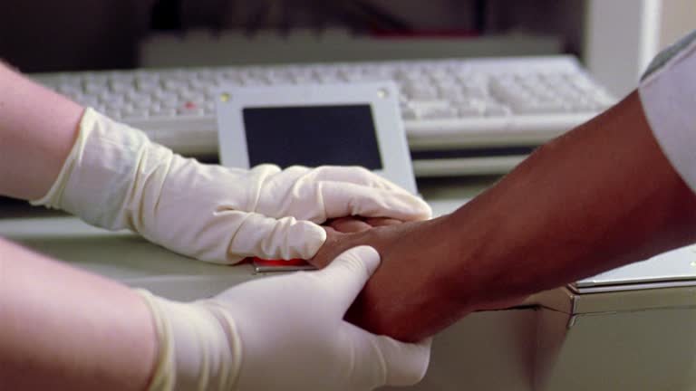 Hands in rubber gloves place a man's fingers on a fingerprint scanner. Hands in rubber gloves place a man's fingers on a fingerprint scanner.
